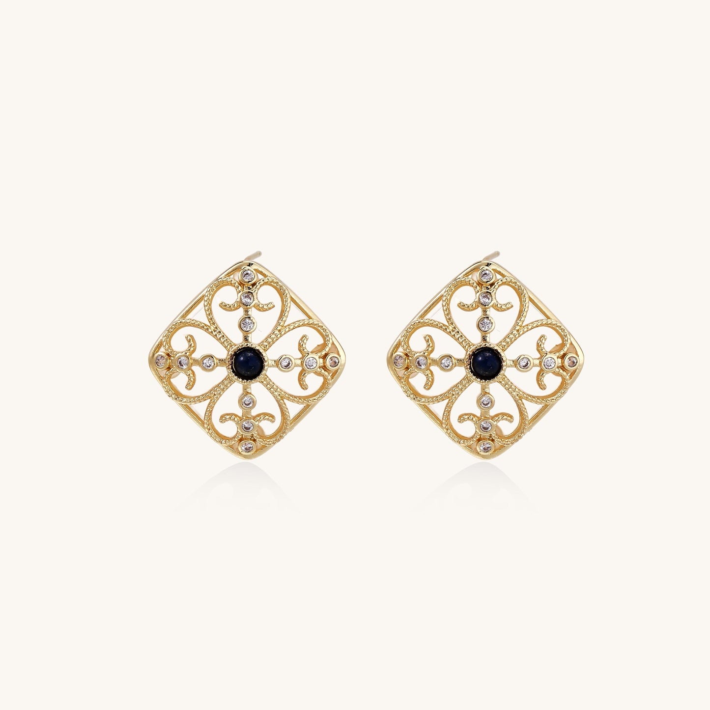 Ornate 18K gold plated stud earrings with intricate filigree design and central lapis lazuli stones on cream background.