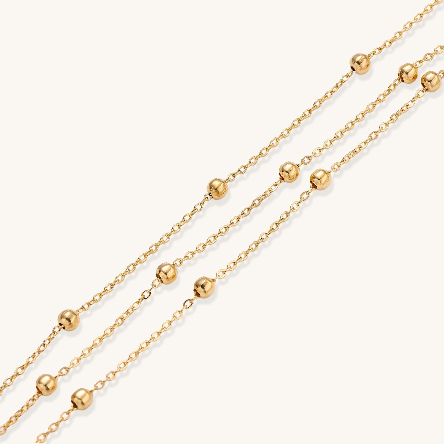 Delicate 18K gold plated bracelet with spherical beads on layered chains and adjustable extender on white background