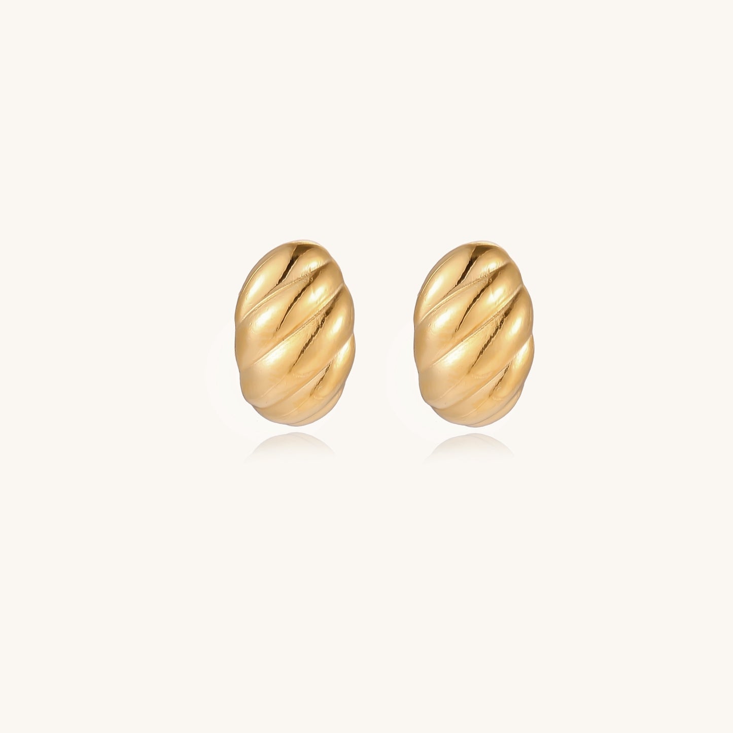 Pair of gold-plated twisted stud earrings with sculptural spiral design displaying elegant curved ridges on cream background.
