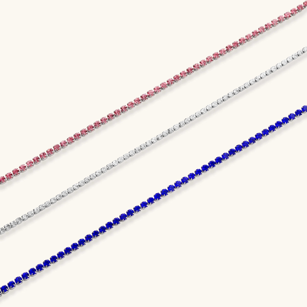 Pink zircon tennis bracelet with silver-tone stainless steel setting and lobster clasp extender chain, flat lay.