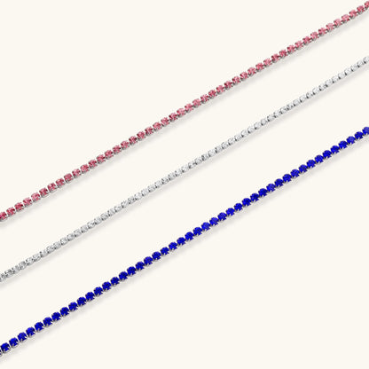 Pink zircon tennis bracelet with silver-tone stainless steel setting and lobster clasp extender chain, flat lay.