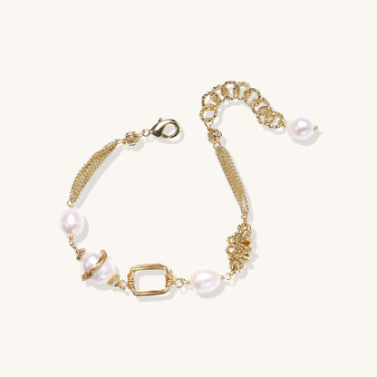 Gold-plated bracelet featuring cream freshwater pearls and decorative chain links on white background.
