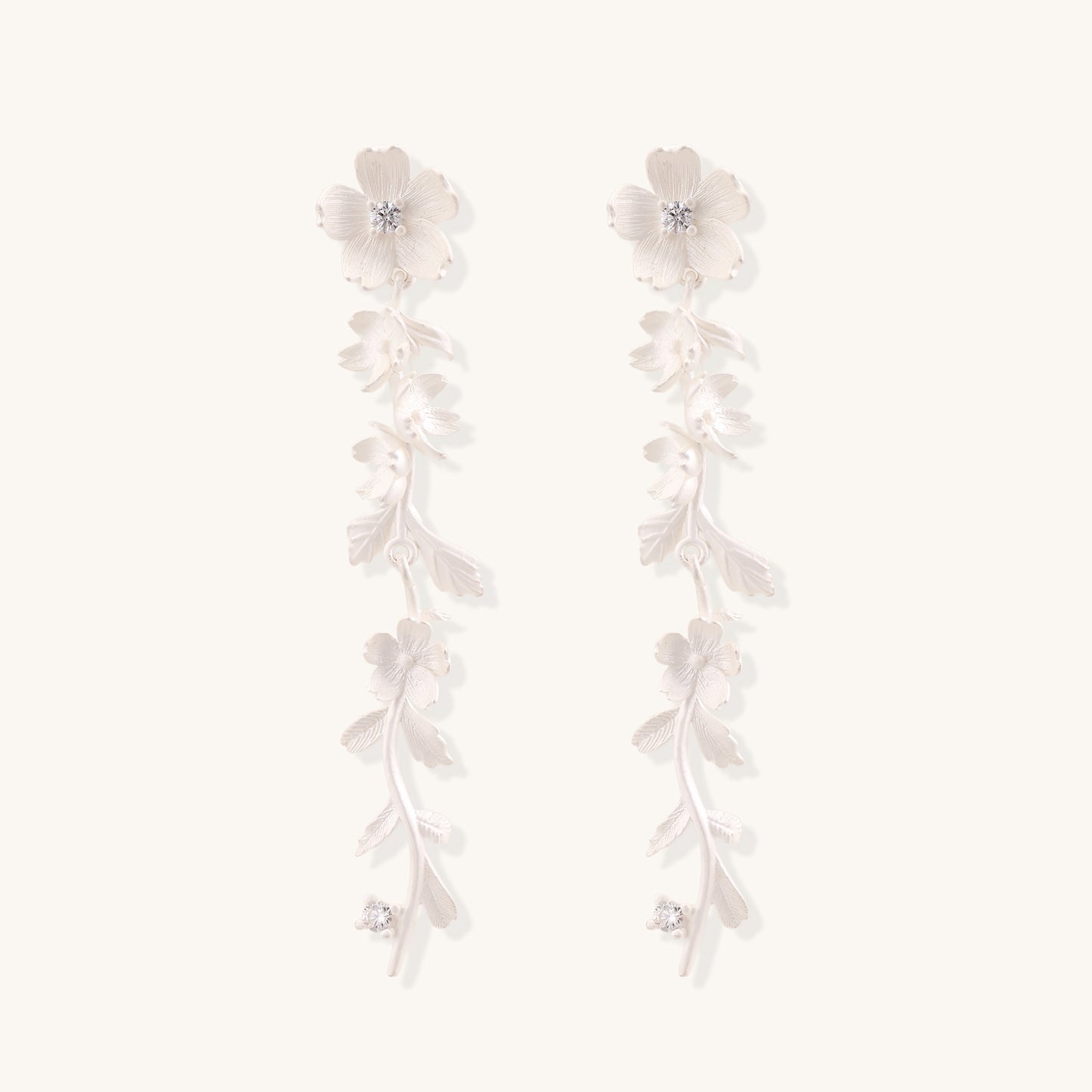 Pair of sterling silver dangle earrings with intricate leaf vine patterns and crystal accents on white background.