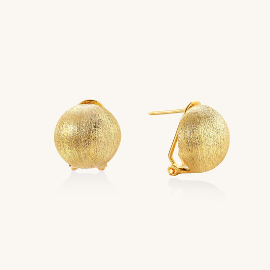 Close-up of textured gold-plated sterling silver dome clip-on earrings with brushed finish on white background.