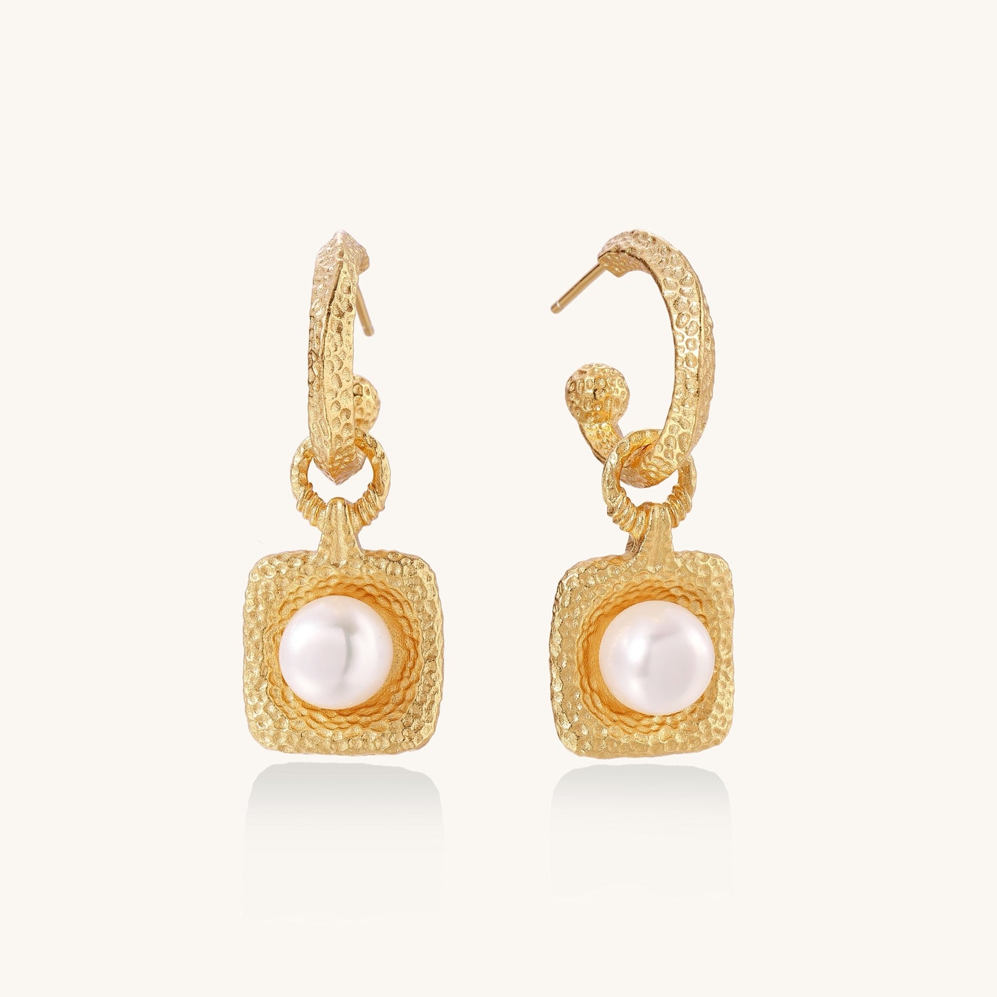 Gold-plated textured hoop earrings with square pendants containing freshwater pearls on white background