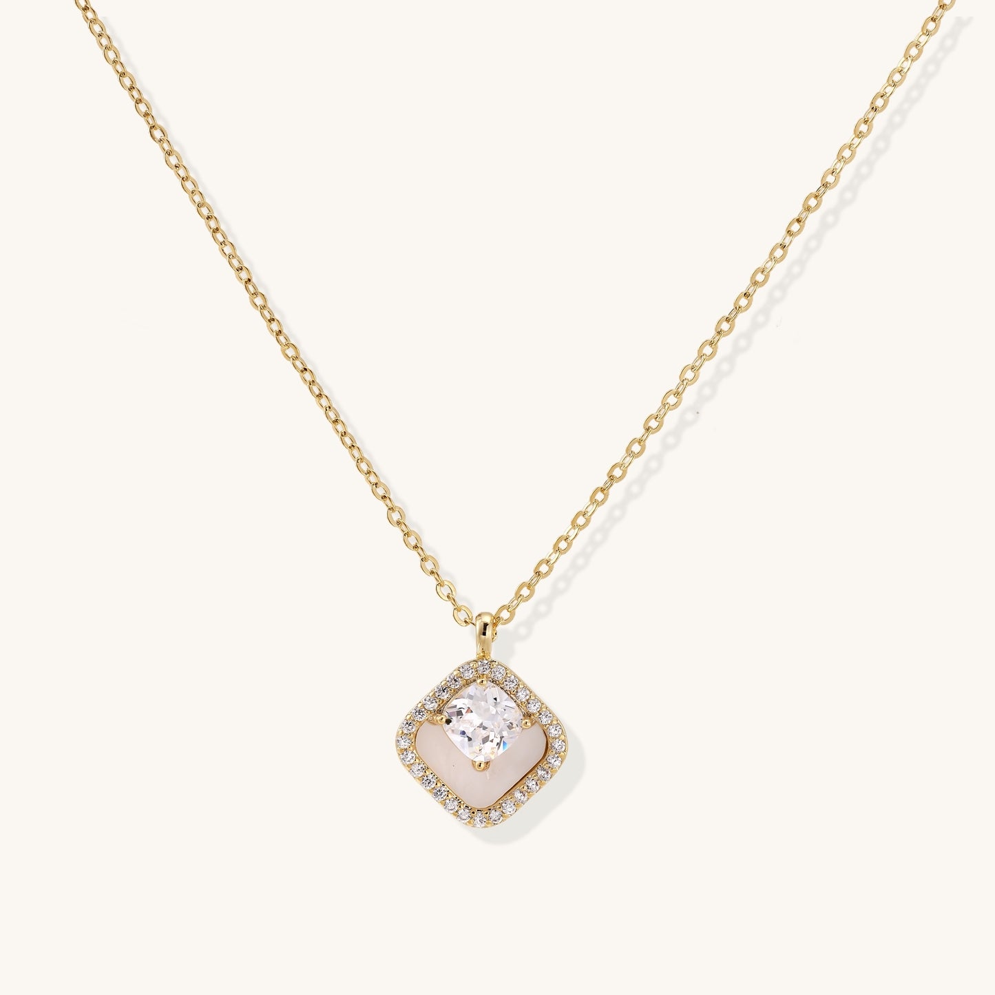 Gold-plated necklace with cushion-shaped pendant featuring a freshwater pearl surrounded by crystal halo on white background.