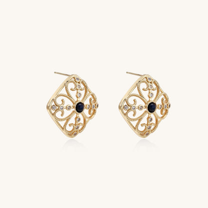Ornate 18K gold plated stud earrings with intricate filigree design and central lapis lazuli stones on cream background.
