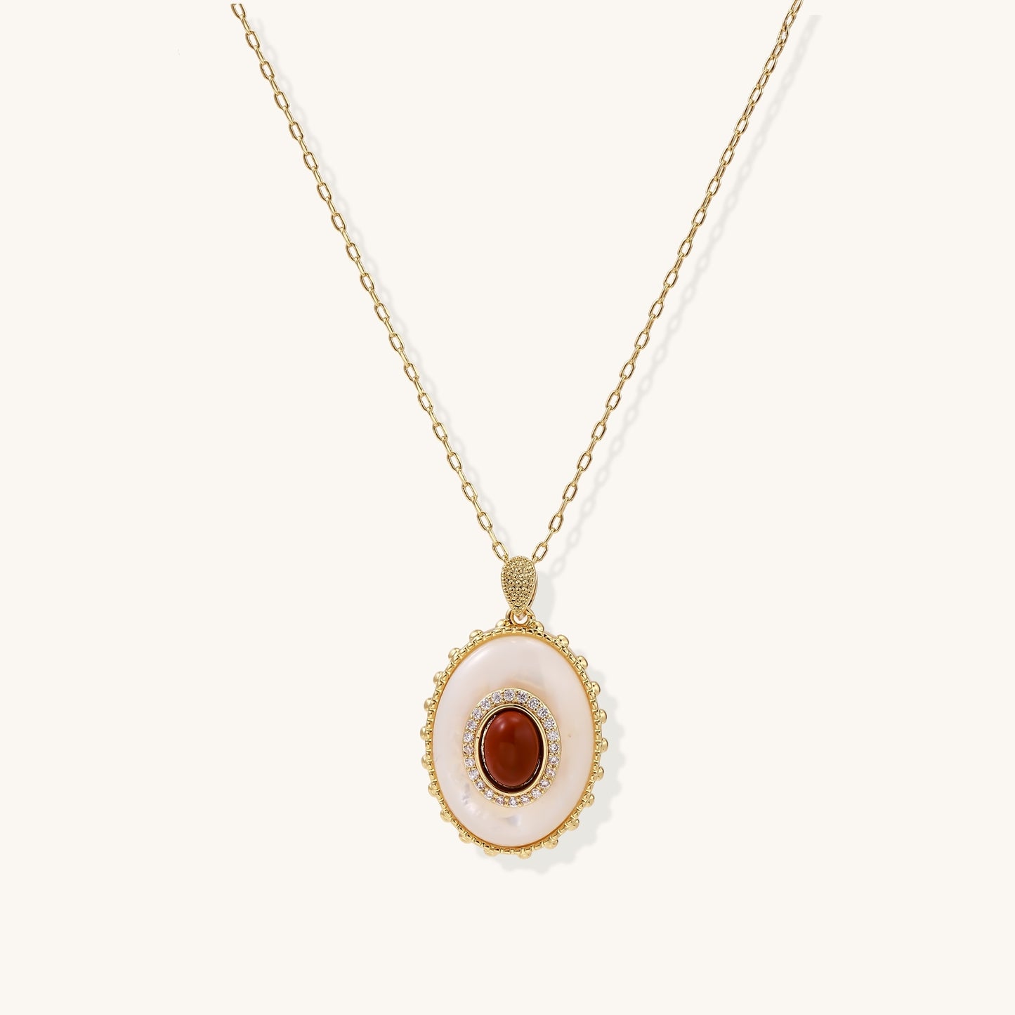 Oval gold-plated pendant featuring mother-of-pearl base with carnelian center stone and crystal accents on delicate chain