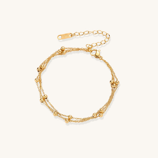 Delicate 18K gold plated bracelet with spherical beads on layered chains and adjustable extender on white background