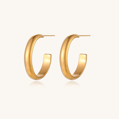 Four pairs of gold-plated stainless steel earrings including hoops and studs displayed on cream background