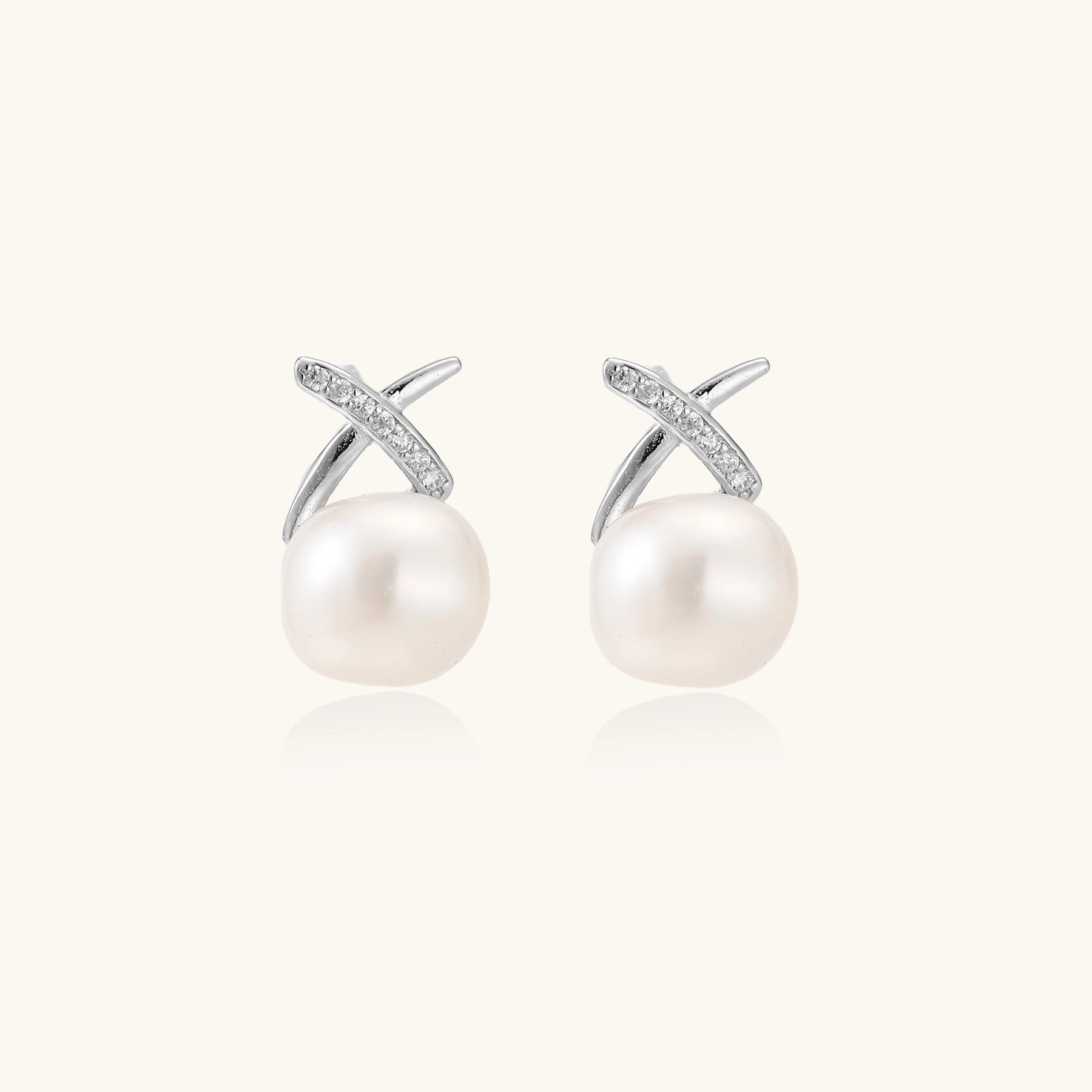 Sterling silver cross-shaped stud earrings with round freshwater pearls dangling below on white background.