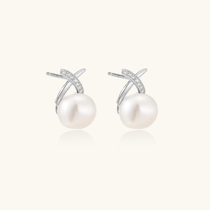 Sterling silver cross-shaped stud earrings with round freshwater pearls dangling below on white background.