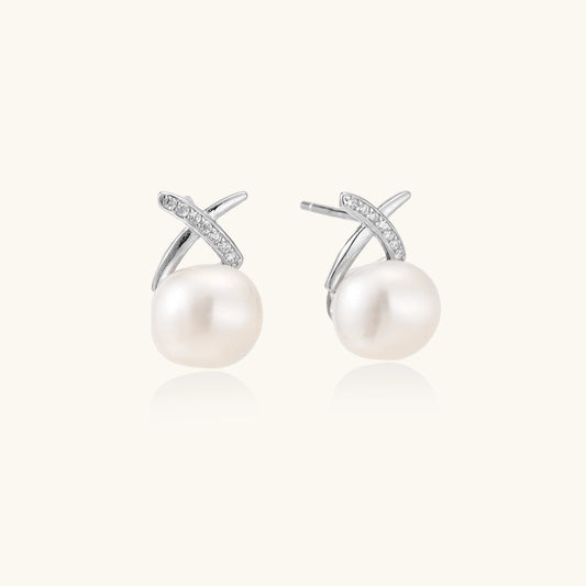 Sterling silver cross-shaped stud earrings with round freshwater pearls dangling below on white background.