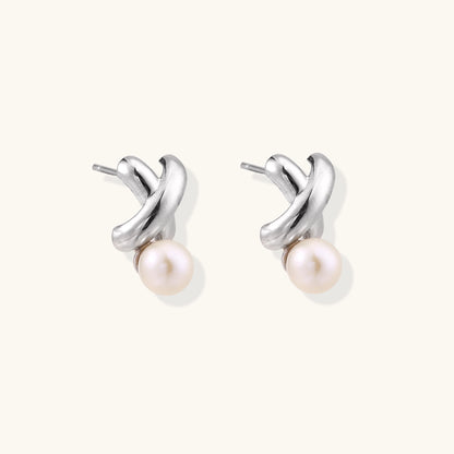 Sterling silver twisted stud earrings with round freshwater pearls on cream background, showing polished finish