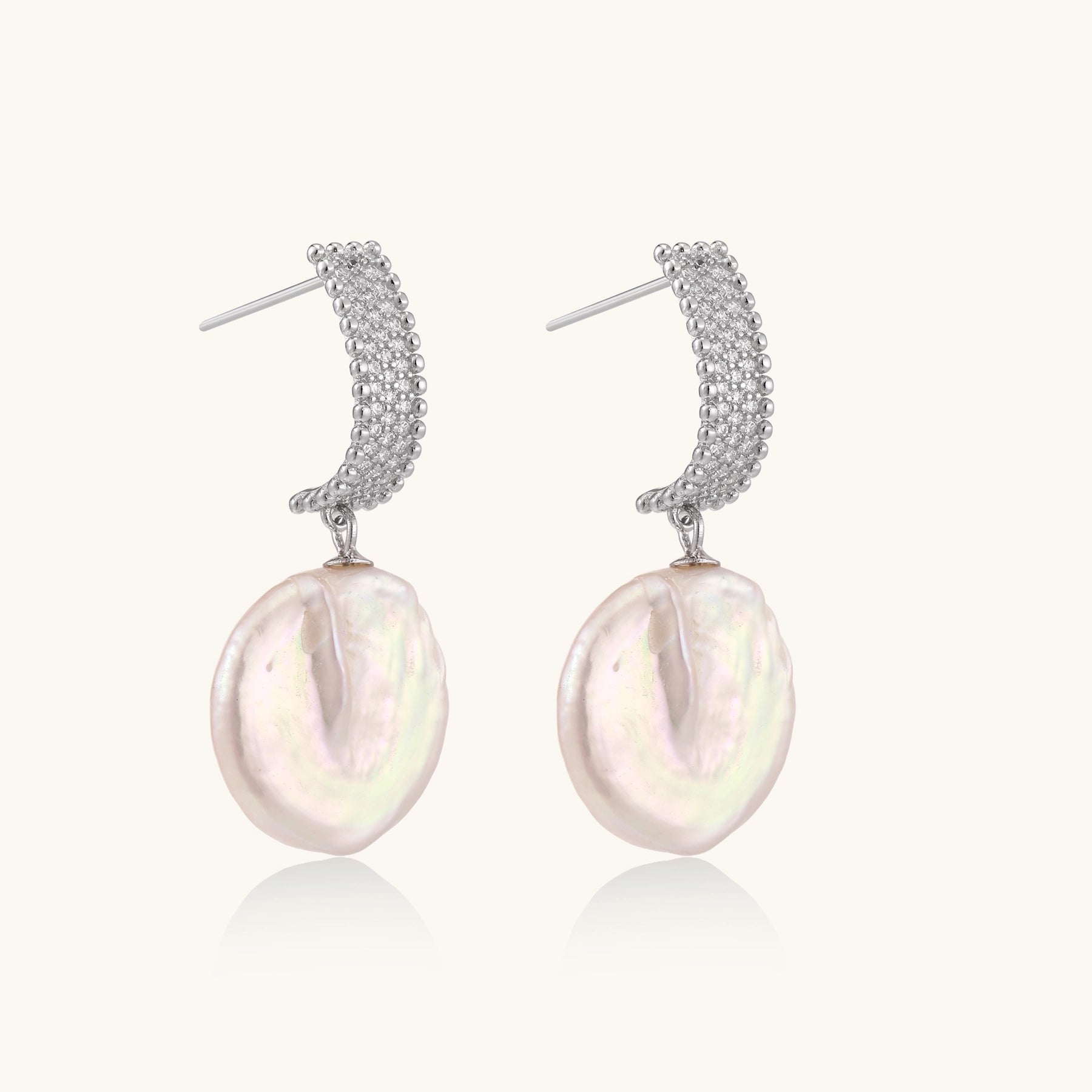 Sterling silver huggie earrings with lustrous baroque pearls displaying iridescent pink and cream tones on white background.