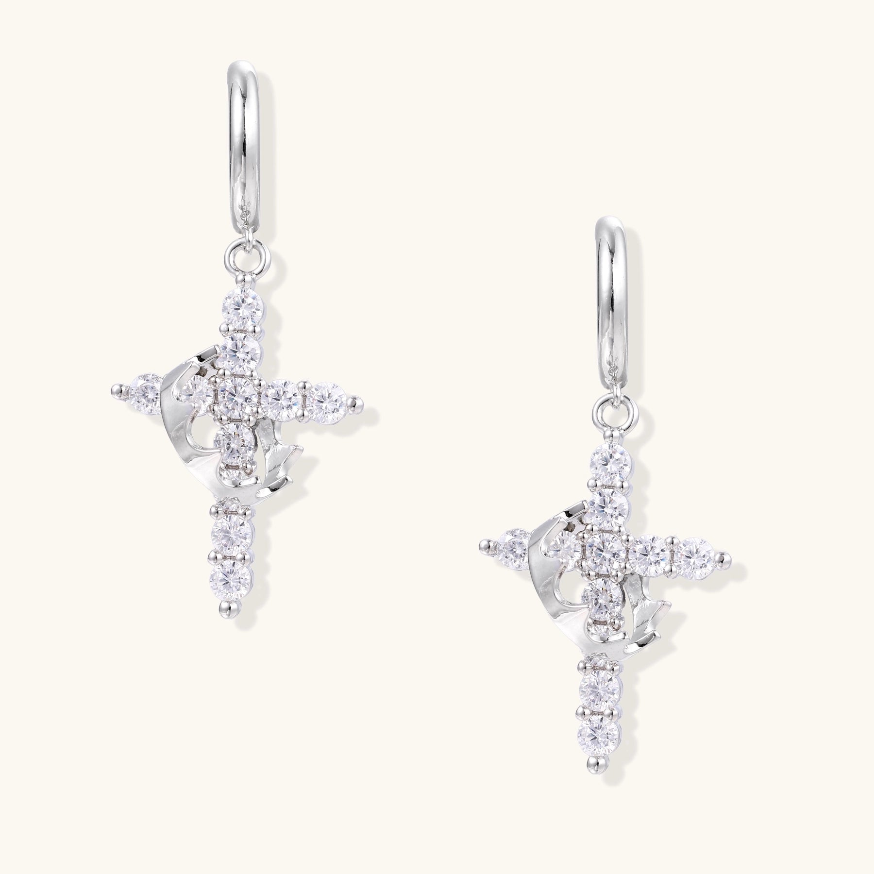 Ornate cross dangle earrings with zirconia stones and gold-plated brass construction on white background.