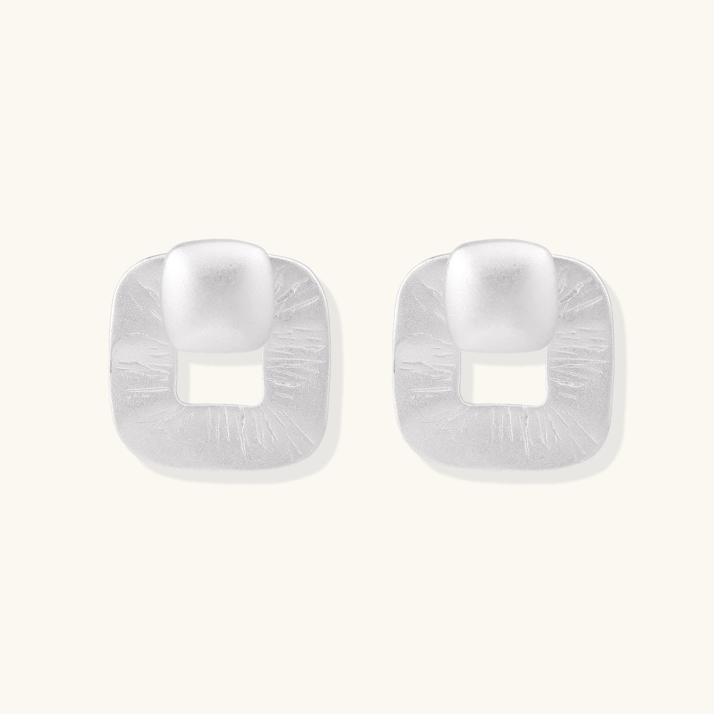 Geometric sterling silver square stud earrings with brushed texture and central square cutouts on white background.