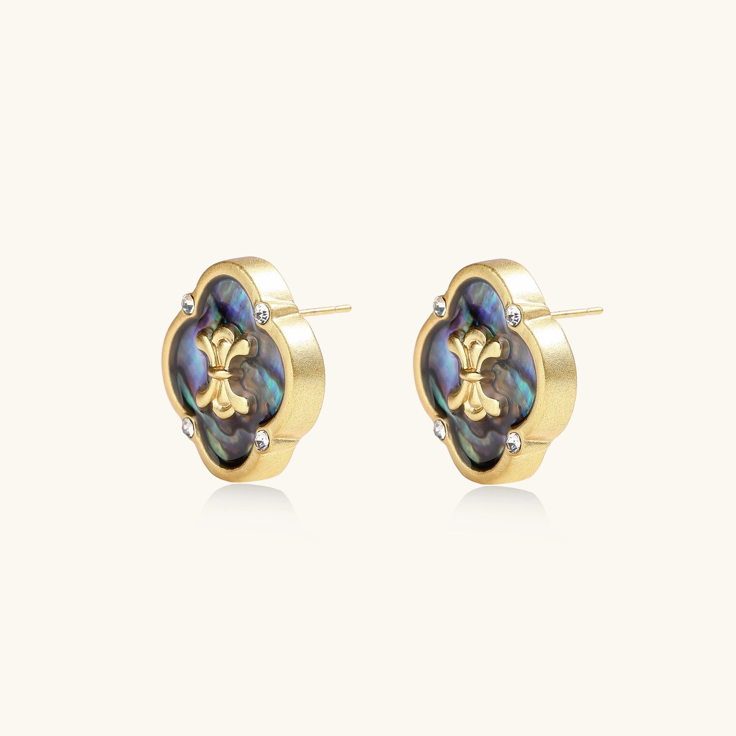 Gold-plated quatrefoil stud earrings featuring iridescent abalone shell centers with decorative motifs and crystal accents