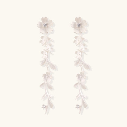 Long sterling silver drop earrings with delicate floral vine design and crystal accents on white background