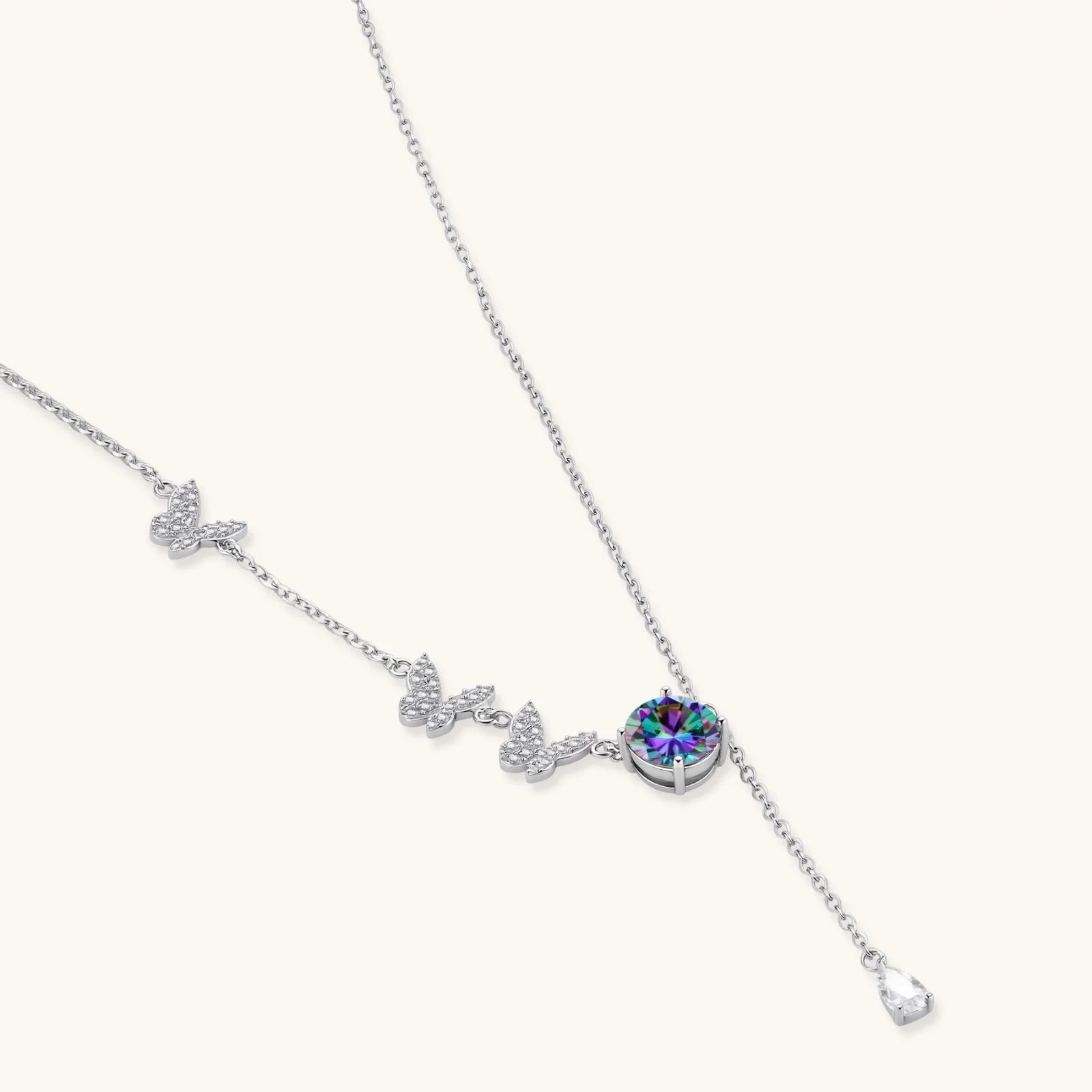Delicate sterling silver necklace with crystal-set butterfly charms and rainbow moissanite pendant on white background.