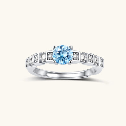 Geometric sterling silver ring with light blue moissanite center stone and square diamond accents on white background