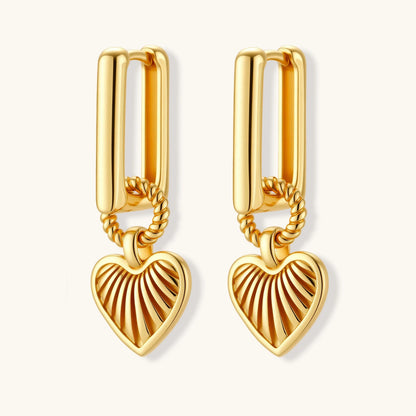 Gold-plated huggie earrings with textured heart charms featuring radiating sunburst patterns on white background.