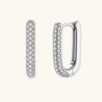 Close-up of platinum-plated sterling silver huggie hoops with pavé crystal setting on white background.