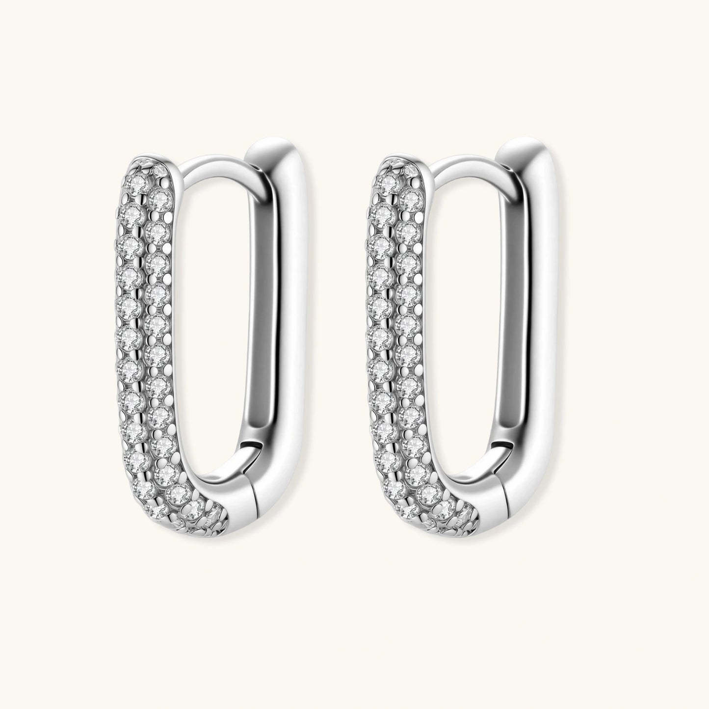 Close-up of platinum-plated sterling silver huggie hoops with pavé crystal setting on white background.