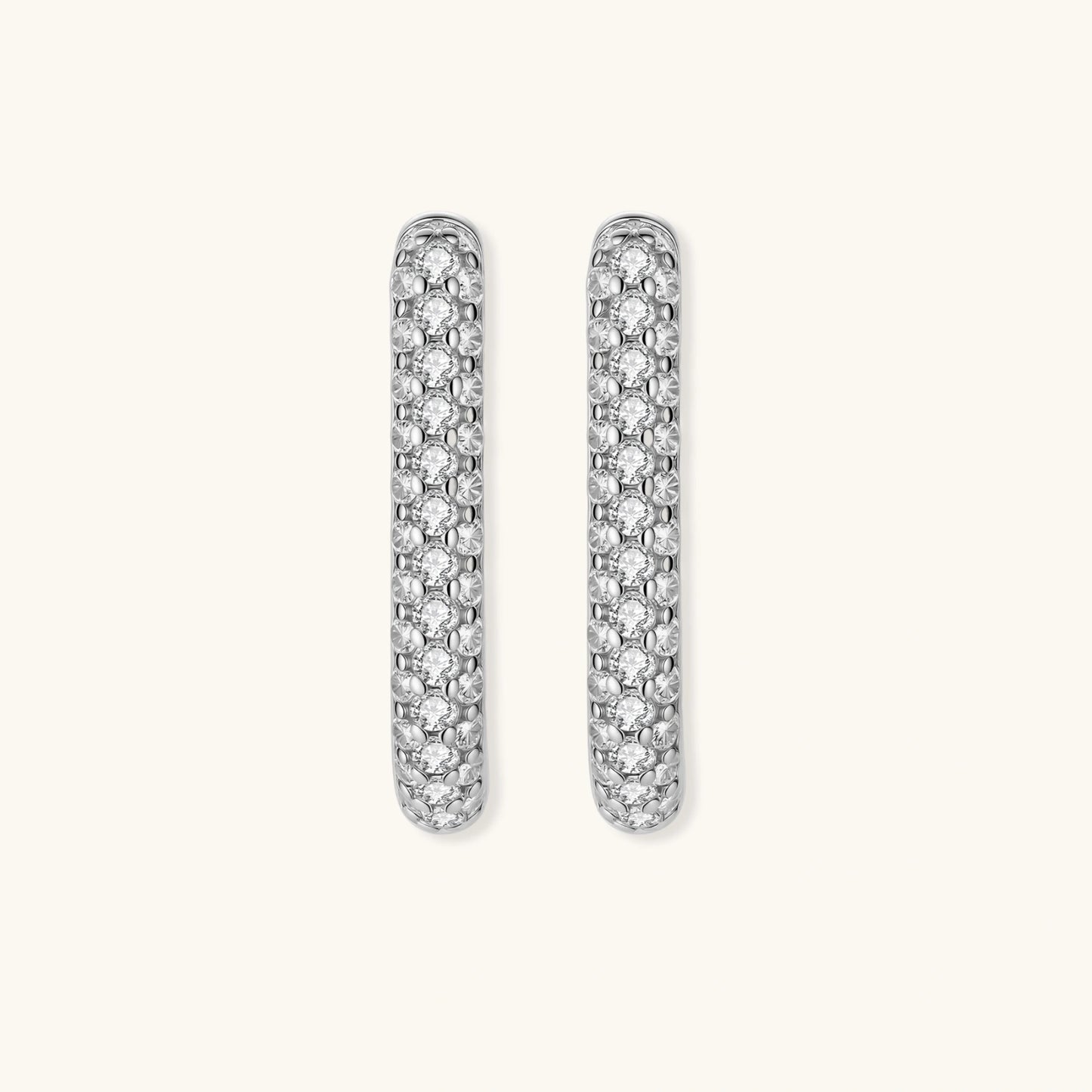 Close-up of platinum-plated sterling silver huggie hoops with pavé crystal setting on white background.
