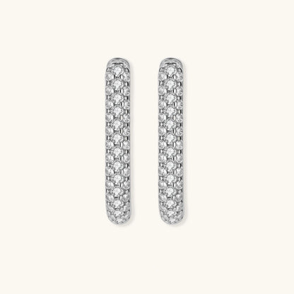 Close-up of platinum-plated sterling silver huggie hoops with pavé crystal setting on white background.