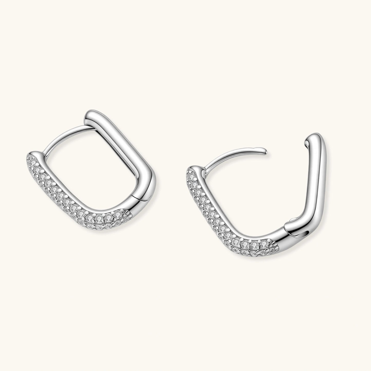 Close-up of platinum-plated sterling silver huggie hoops with pavé crystal setting on white background.
