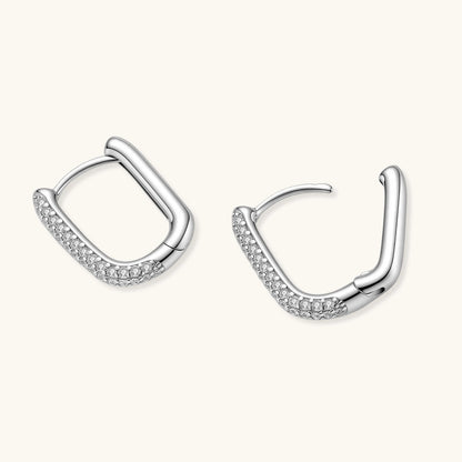 Close-up of platinum-plated sterling silver huggie hoops with pavé crystal setting on white background.