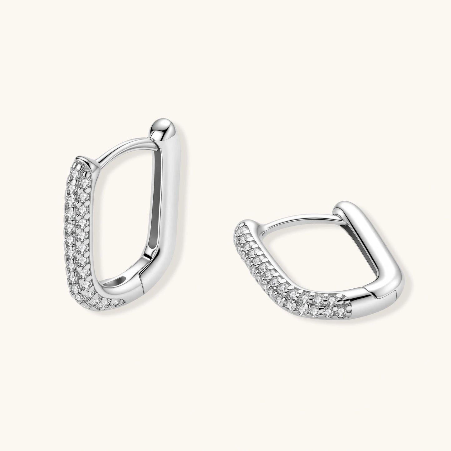 Close-up of platinum-plated sterling silver huggie hoops with pavé crystal setting on white background.