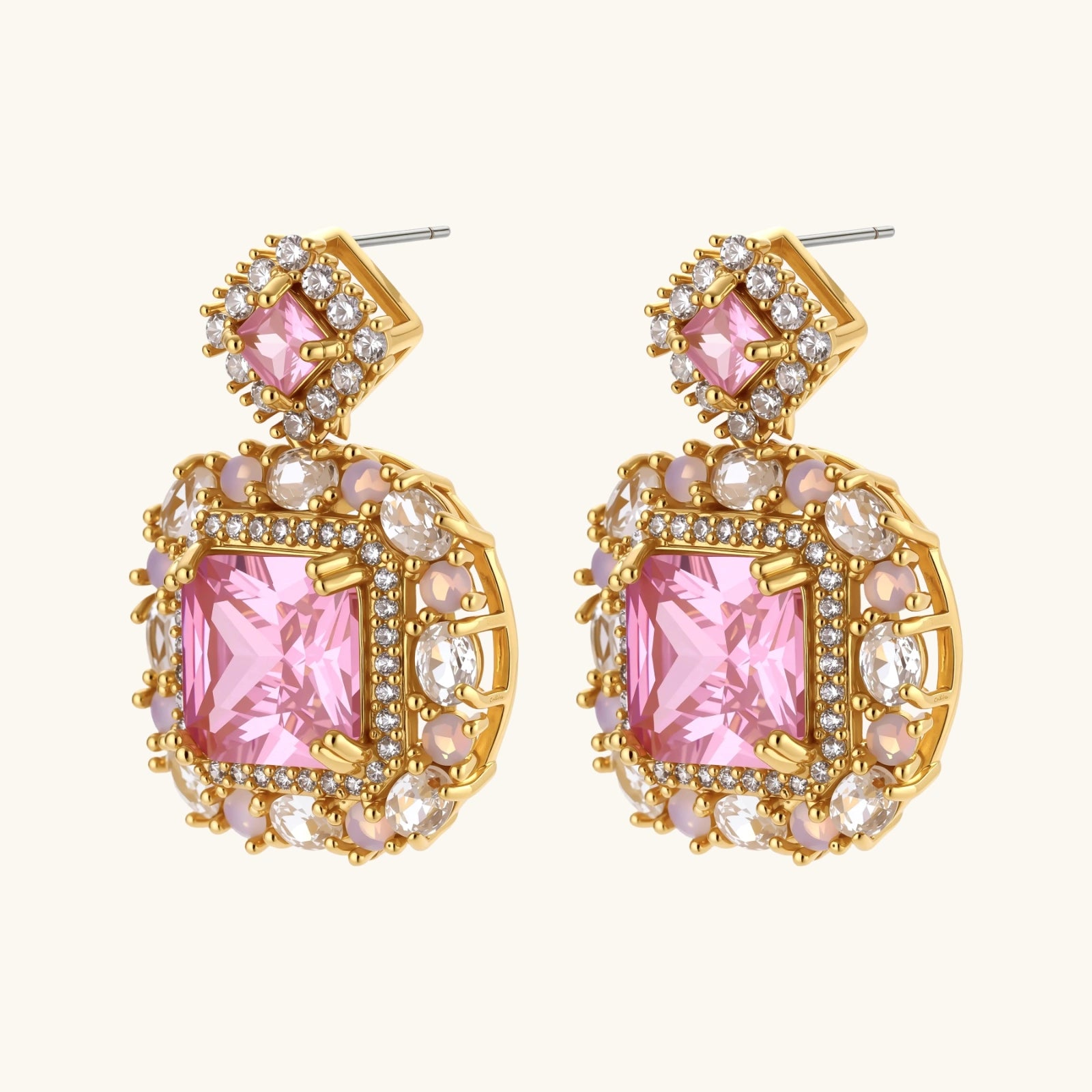 Ornate gold-plated jewelry set with rose pink zirconia center stones and crystal accents on cream background.