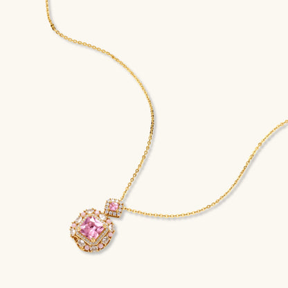 Ornate gold-plated jewelry set with rose pink zirconia center stones and crystal accents on cream background.