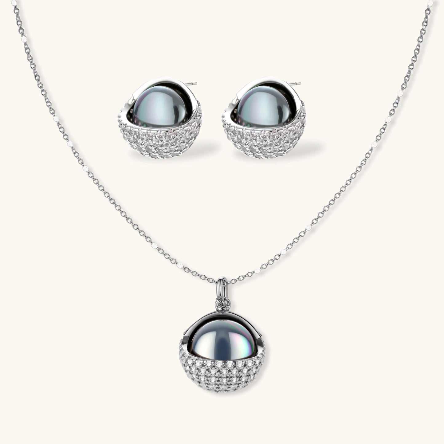 White gold plated spherical jewelry set with zirconia crystal pavé and dark lustrous centers on neutral background.