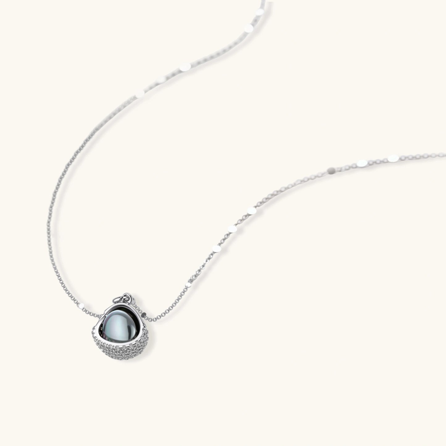 White gold plated spherical jewelry set with zirconia crystal pavé and dark lustrous centers on neutral background.