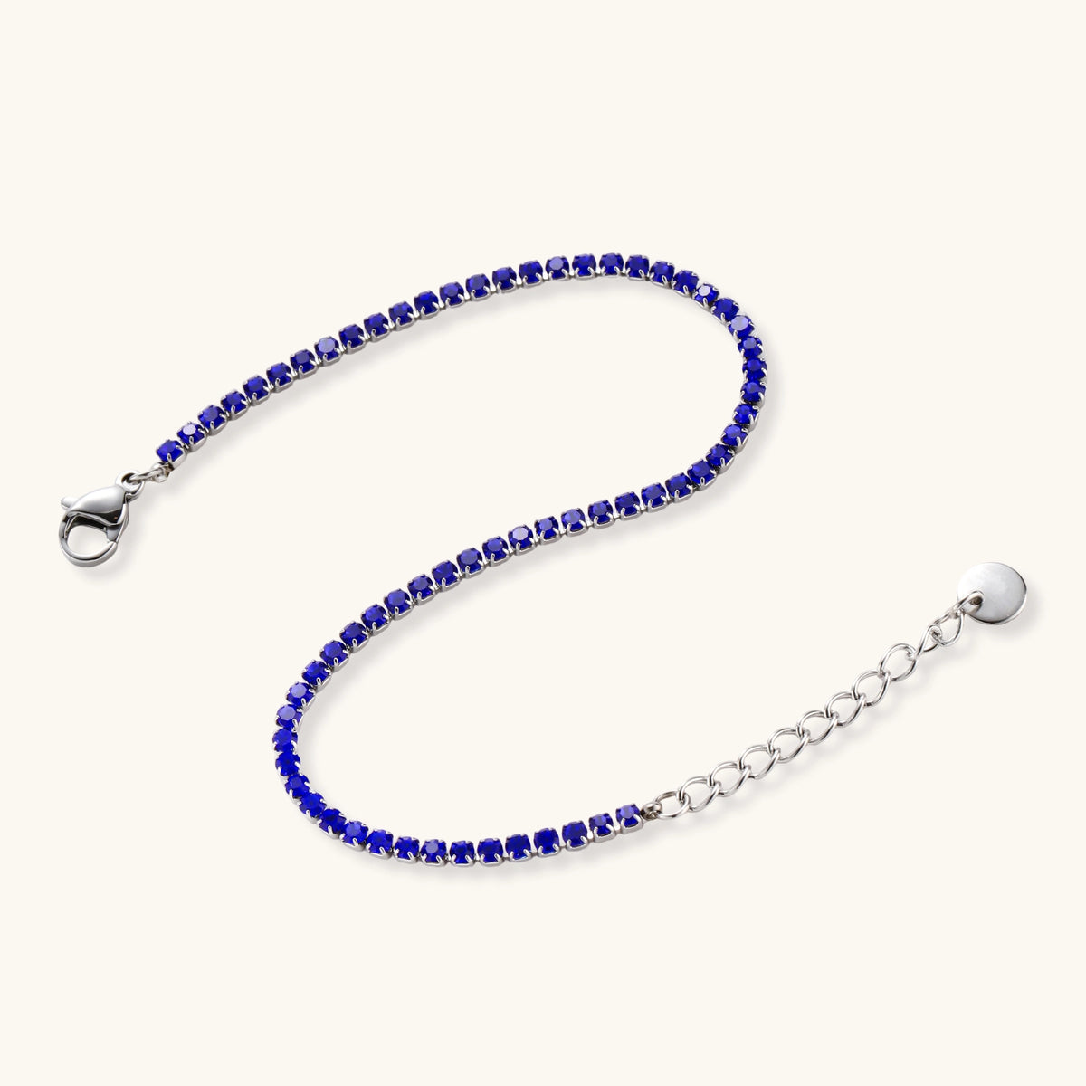 Slim stainless steel tennis bracelet set with vivid cobalt blue round zircon stones and a lobster clasp with extender chain.